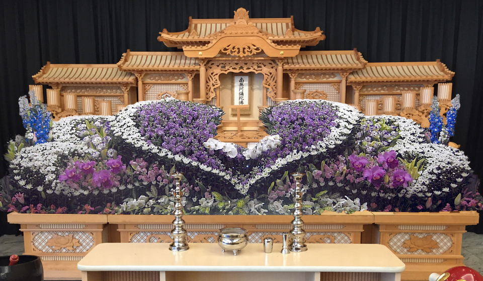 市民葬祭アステルの祭壇に白と紫を基調に整えた花祭壇が並び、宇都宮市 葬儀向けのFAN倶楽部入会特典で割引対象となる葬儀式場の装花例を示す