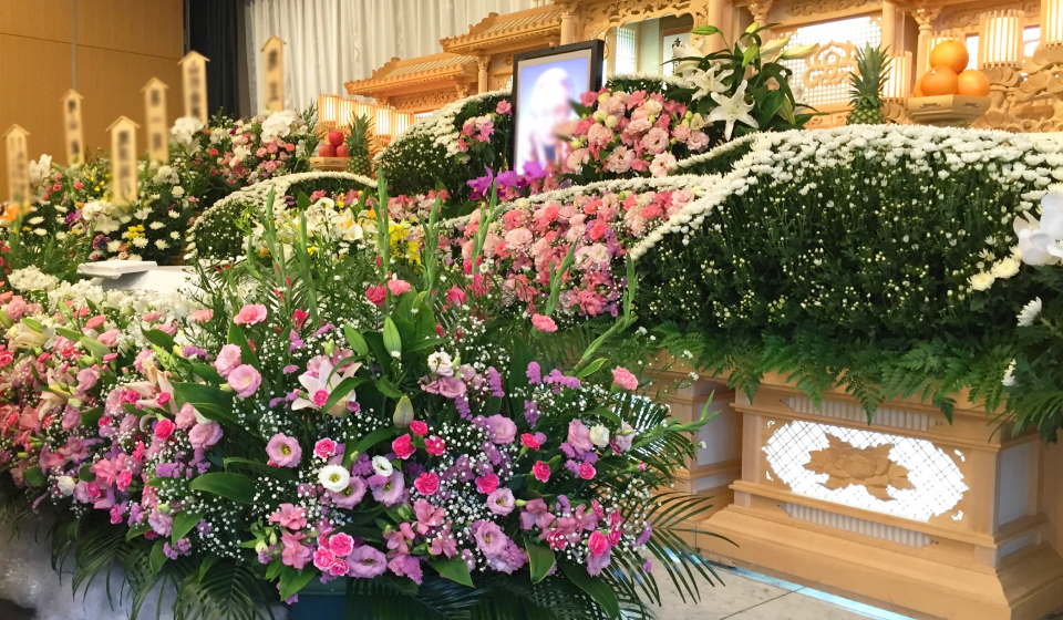 市民葬祭アステルのFAN倶楽部特典紹介ページ用、祭壇前にピンクと白の花で飾られた葬儀会場の全景写真、宇都宮市 葬儀の案内に使う仏花と祭壇の設えを示す画像。