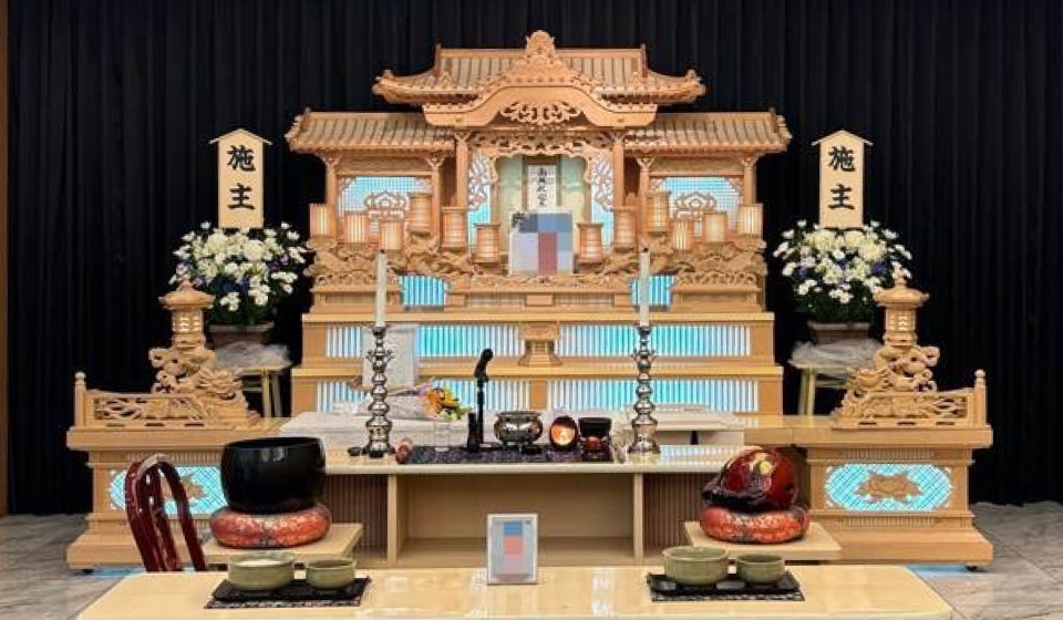 市民葬祭アステルが提供する宇都宮市の祭壇例、白木造りの三段祭壇に供花と仏具を配した葬儀会場の設営風景、FAN倶楽部特典で施主花や祭壇割引の案内に合う展示